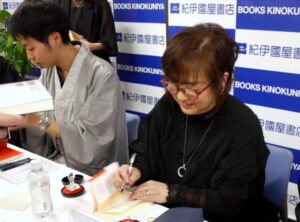 受賞作の『お内儀さんこそ、心に鬼を飼ってます　おけいのfesta』にサインをする麻宮好氏